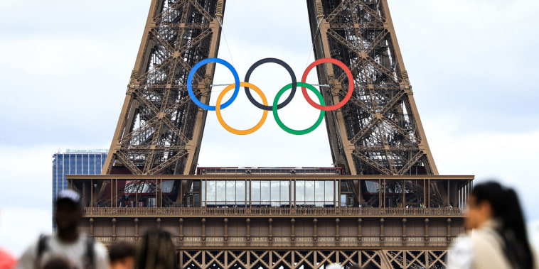 The Olympic rings on the Eiffel Tower as people walk past