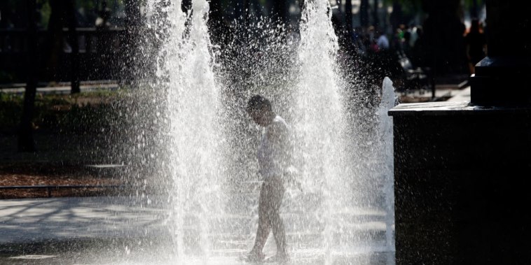 A child cools off by getting wet in a fountain at the