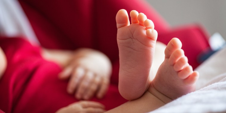 Baby feet in baby carriage dressed in red.