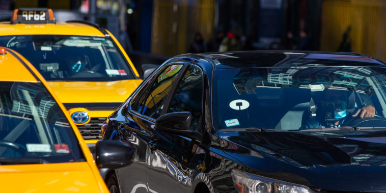 Yellow cabs and Uber car drive through Times Square. 