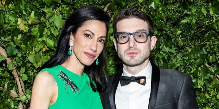 Huma Abedin and Alexander Soros pose together on the green carpet in front of foliage