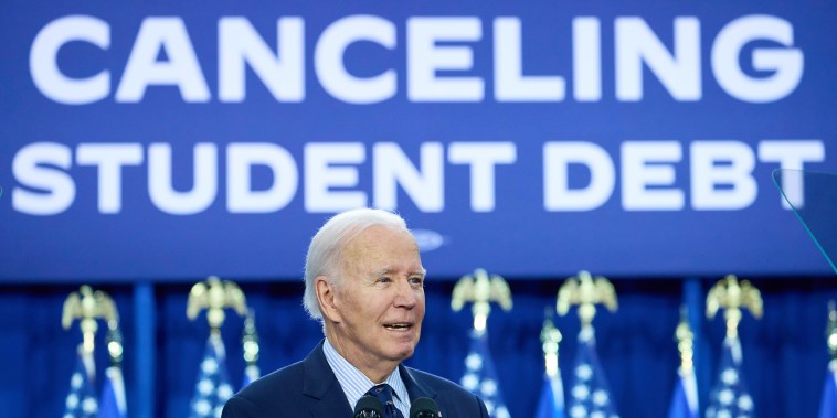  Joe Biden speaks in front of a sign that reads "President Joe Biden Cancelling Student Debt"