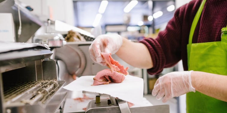 Employee in general store weighing sliced meat in kitchen