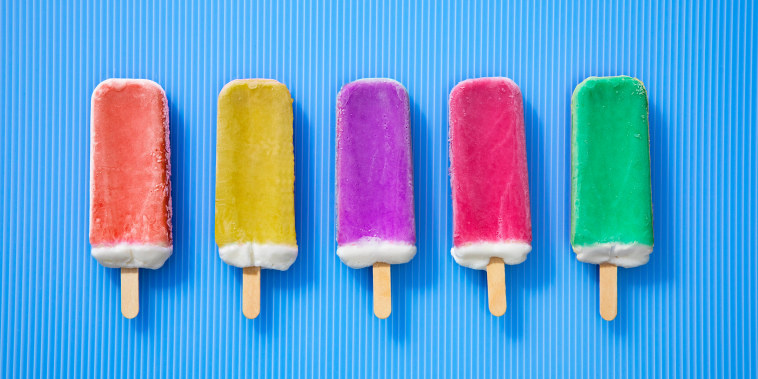 Rainbow ice cream popsicles in a Row on a blue background.