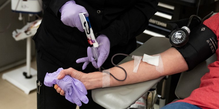 A phlebotomist draws blood from a donor