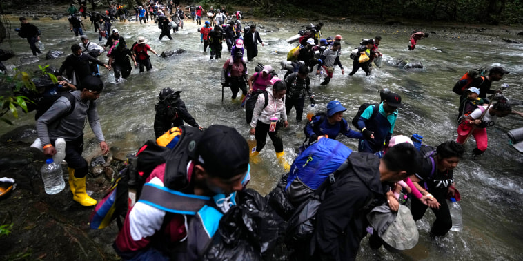 Migrants, mostly Venezuelans, cross a river during their journey through the Darien Gap from Colombia into Panama, on Oct. 15, 2022.