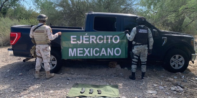 Dos uniformados posan ante el vehículo que según las autoridades fue utilizado en el ataque y varios cargadores de fusil.