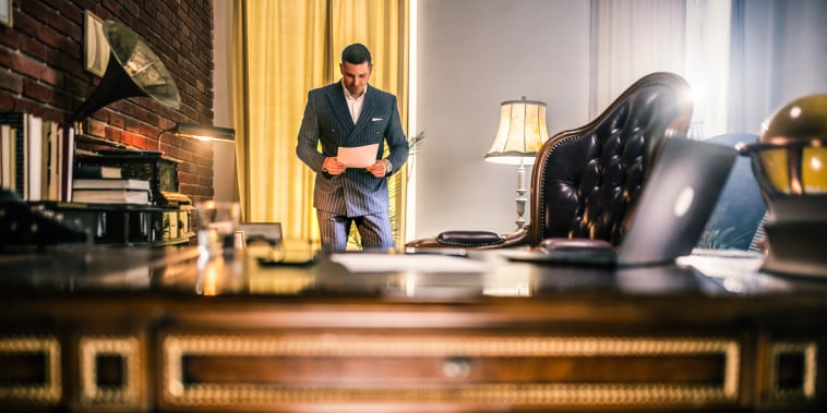 Businessman reading documents and uses the phone and computer in the office