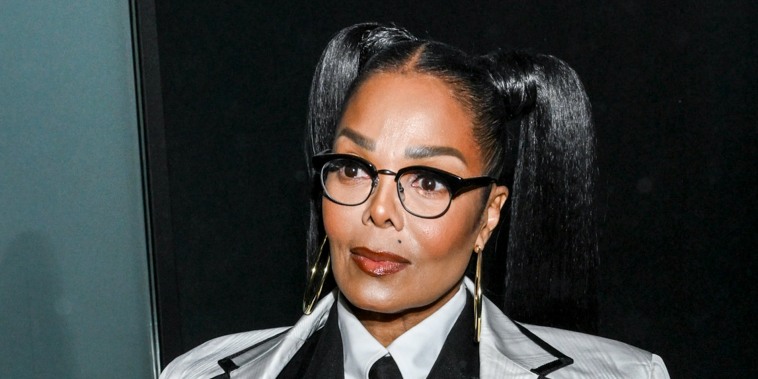 Janet Jackson looks ahead wearing glasses and a white blazer