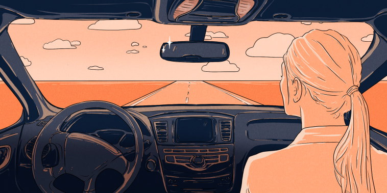 POV as if the viewer is sitting in the back of a car. A woman is seated in the passenger seat, and there is no driver behind the wheel. Through the window we see a coral-colored sky and a road leading into the distance.