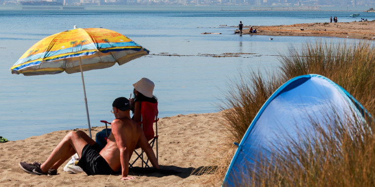 Residents lounge near the water on Alameda Beach