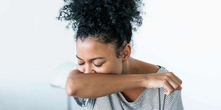 Young woman sneezing in elbow