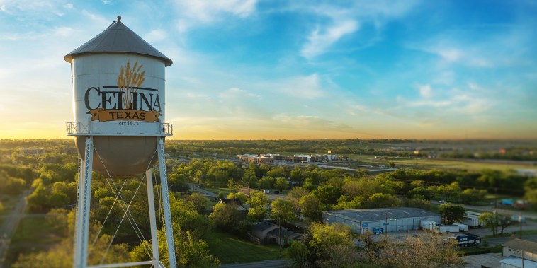 A water tower against a blue sky and overseeing the city