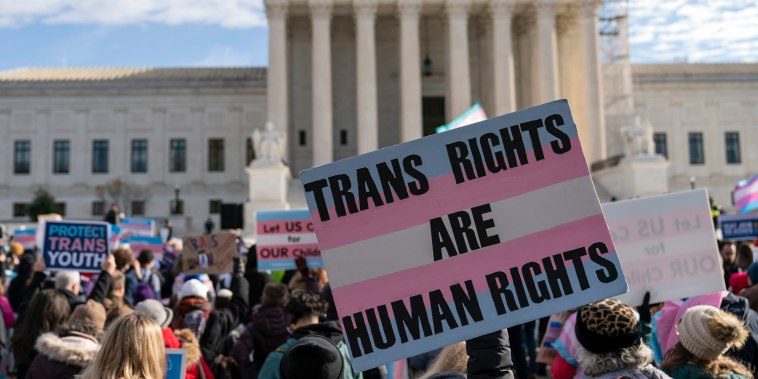 Transgenders rights supporters rally outside of the Supreme Court, a sign is held saying "Trans Rights Are Human Rights"