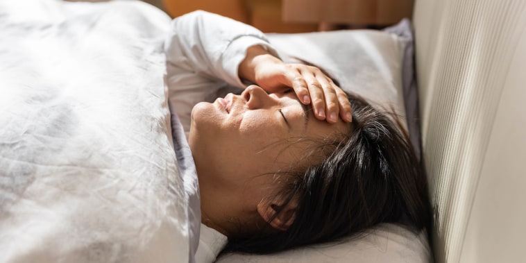 A woman lying in bed, feeling unwell and alone