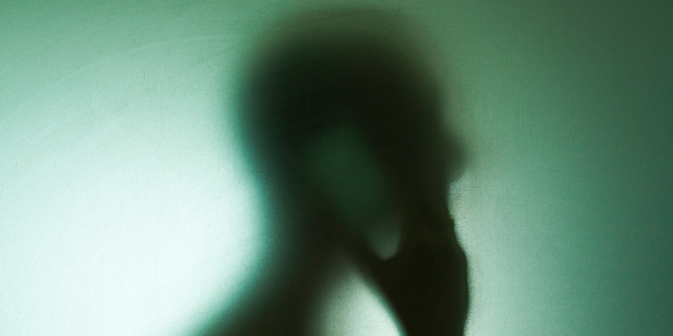 Man using mobile phone obscured behind glass.