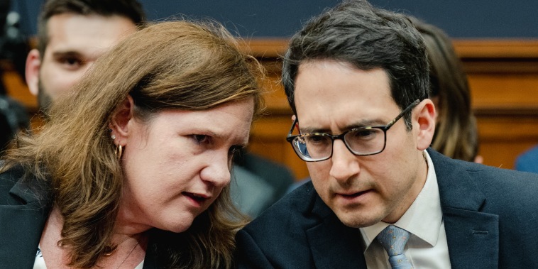 Rebecca Kelly Slaughter, left, chats with Alvaro Bedoya, both are seating inside a building