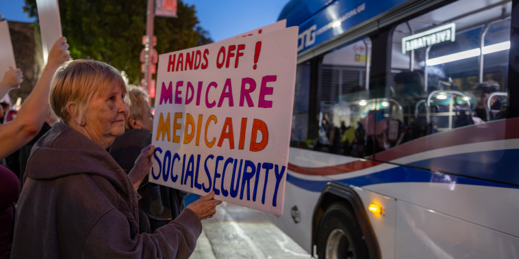 A woman holds a sign expressing fear of cuts to Medicare, Medicaid and Social Security, at a "Hands Off!" protest.