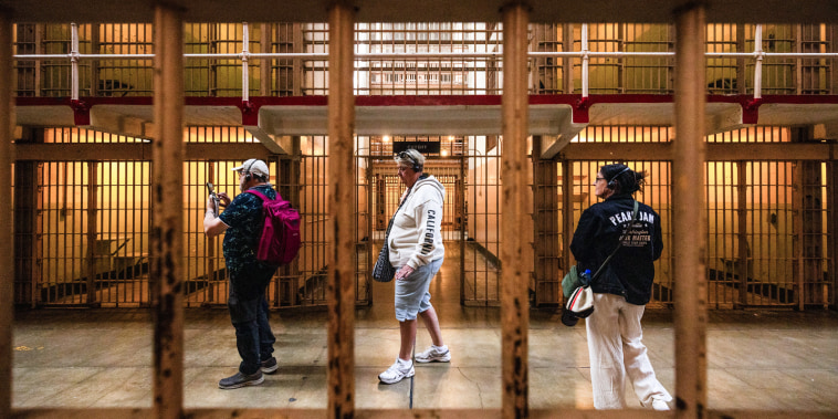 Visitors walk through a cell block of a prison