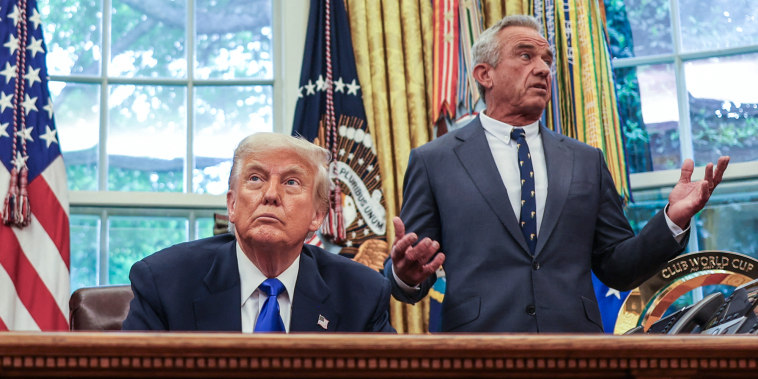 Donald Trump sits at his desk, left, in the oval office while Robert F Kennedy Jr stand behind him and speaks while gesturing