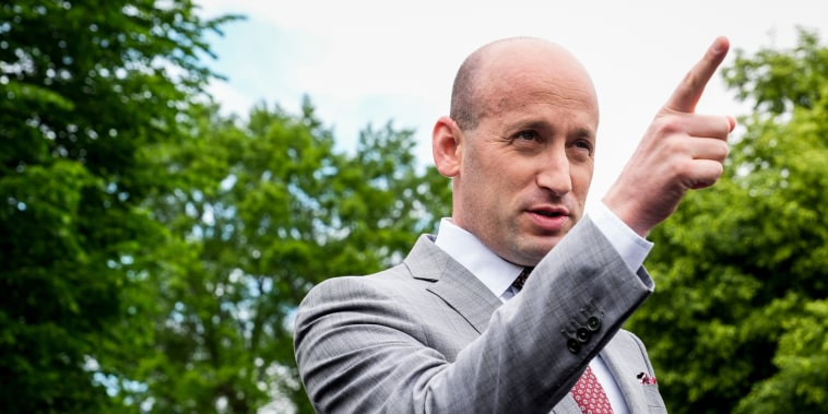 Stephen Miller points while speaking, stands outside