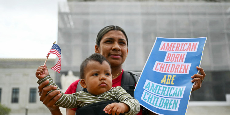 Olga Urbina holds a sign that reads "American Born Children are American Children" as her son Aers holds an American flag.