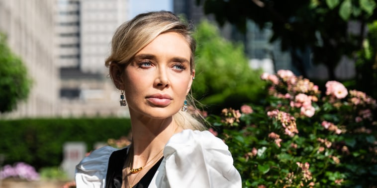 Kaja Sokola seated outside on a terrace near a flowered bush