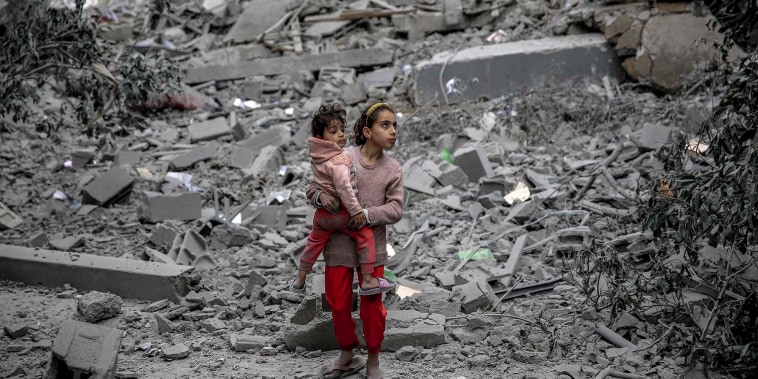A Palestinian girl carries a child through the rubble of houses destroyed by Israeli bombardment in Gaza City 