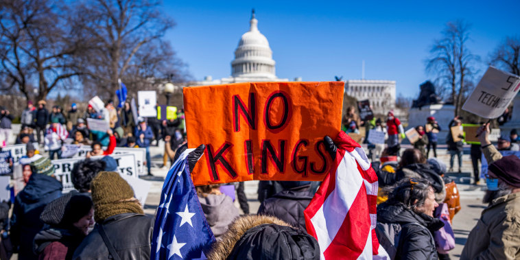 Demonstrators hold signs during the No Kings Day.