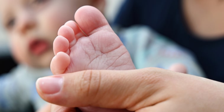 A hand holds a baby's foot