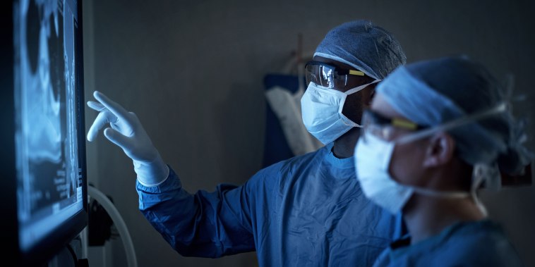 two surgeons analyzing a patient’s medical scans during surgery