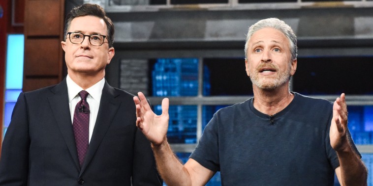 Stephen Colbert, left, and Jon Stewart stand next to each other on stage as Jon speaks
