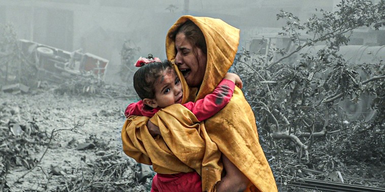 A woman holding a girl reacts after Israeli airstrikes hit