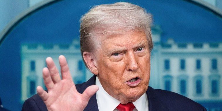 Donald Trump speaks, one hand raised