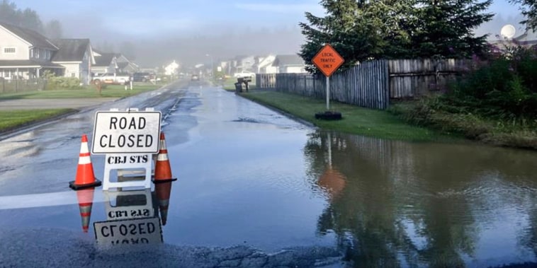 Cones and a road closed sign on a flooded residential street