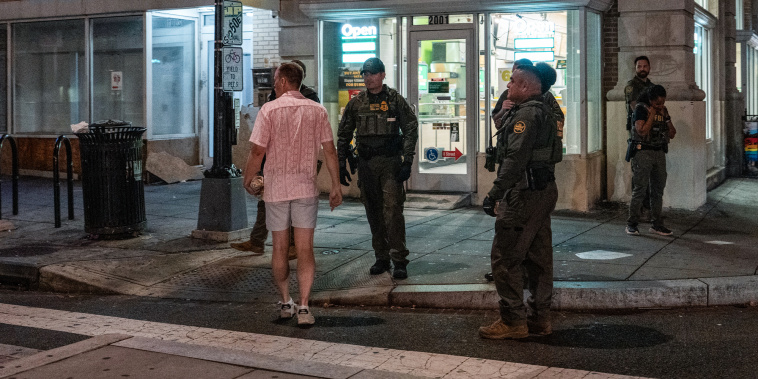 Sean Dunn holds a sandwich as he interacts with Border Patrol and FBI agents outside of a Subway location holding a sandwich