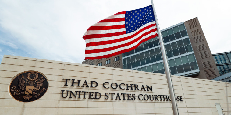 The Thad Cochran United States Courthouse with an American flag at half mast in front of it outside