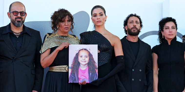 From left, standing next to one another, Amer Hlehel, Kaouther Ben Hania (holding an image of Hin Rajab), Saja Kilani, Motaz Malhees, and Clara Khoury