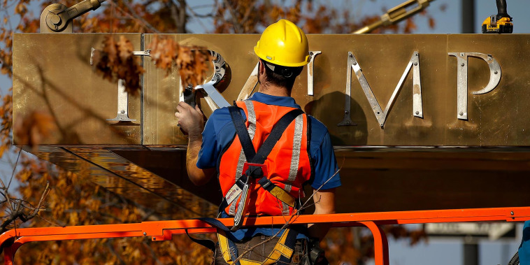 A worker removes the words "Trump Place" from a residential building in New York in 2016. 