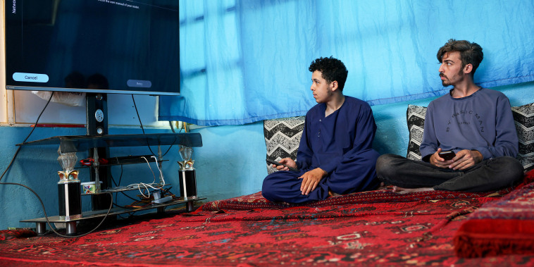 Men try to connect their smart TV to the internet inside their home, amid telecom shutdown across the country, in Kabul