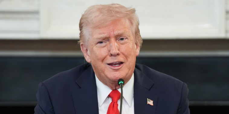 Donald Trump speaks while seated at a table
