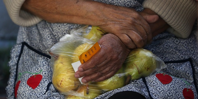 A woman holds a bag of pears as she waits in line to receive free food at the Richmond Emergency Food Bank.