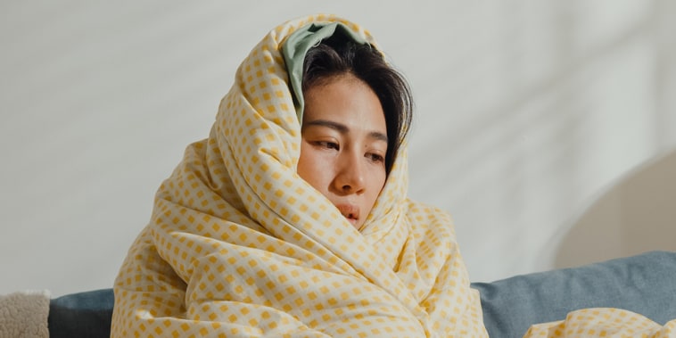 Sick person under the blanket on sofa in living room at home.