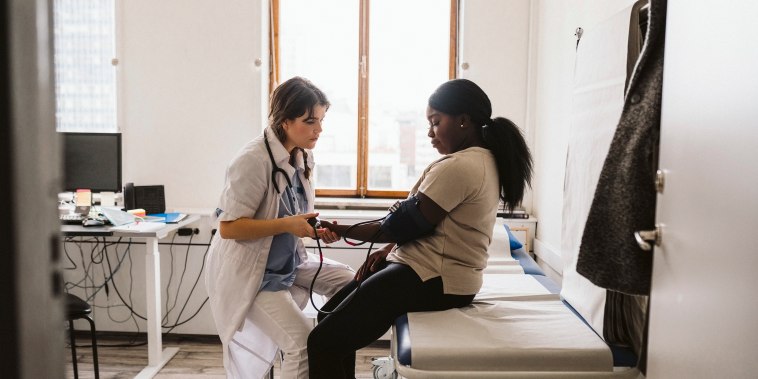 Female healthcare worker measuring young patient's blood pressure in medical clinic