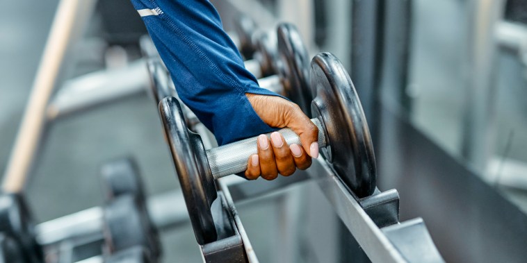 Athlete picking up dumbbell in a gym.