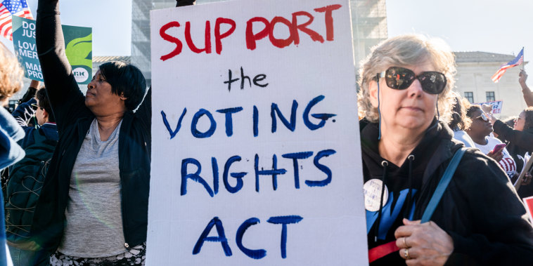 Protestors hold signs outside of the Supreme Court building, one says "Support the voting rights act" and another says "Protect our vote"