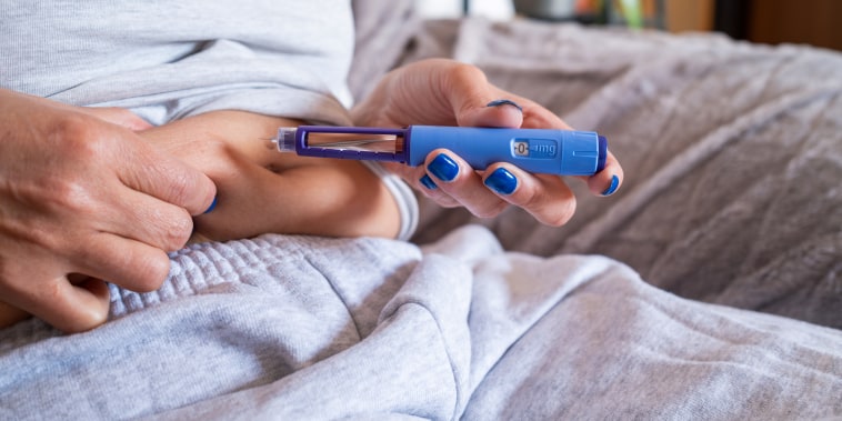 Unrecognizable mature overweight diabetic woman injecting a syringe of semaglutide into her stomach.