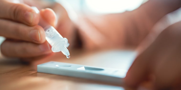 Close up of woman swab COVID-19 testing by Rapid Antigen Test kit and dropping reagent to cartridge at home, Home Isolation.