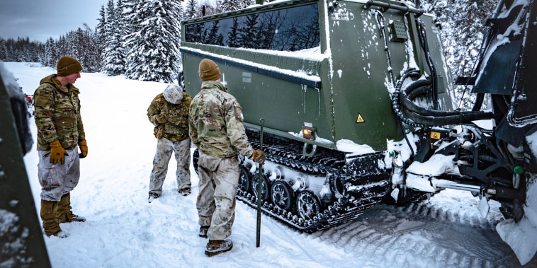 Soldiers from the 11th Airborne Division inspecting a Cold Weather-All Terrain Vehicle in the snow outside