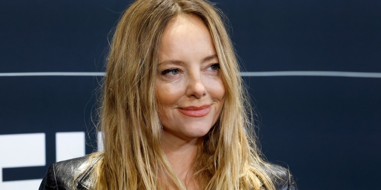 Bijou Phillips smiles in front of a step-and-repeat backdrop.